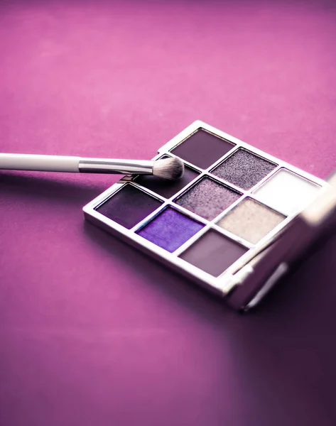 Палитра теней для век и кисть для макияжа на фиолетовом фоне, глаза ш — стоковое фото