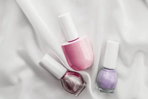 Nail polish bottles on silk background, french manicure products