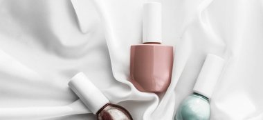 İpek arka planda oje şişeleri, Fransız manikür ürünleri.