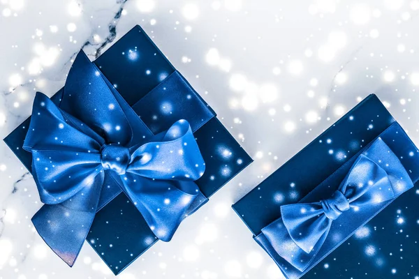 Зимний праздник подарочная коробка с голубой шелковой лук, снег блестки на мраморе — стоковое фото