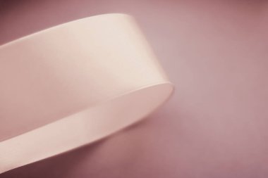 Pastel arka planda soyut kıvrımlı ipek kurdele, özel lüks.