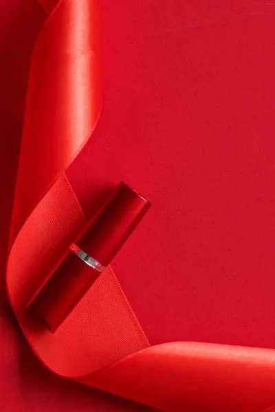 Pintalabios de lujo y cinta de seda sobre fondo rojo de vacaciones, hacer - — Foto de Stock