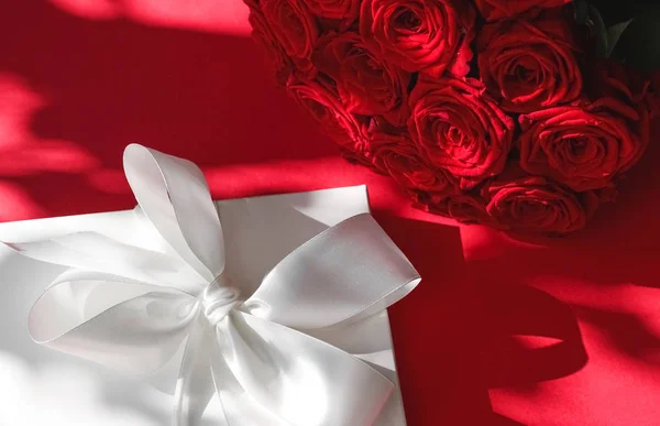 Luxury holiday silk gift box and bouquet of roses on red backgro