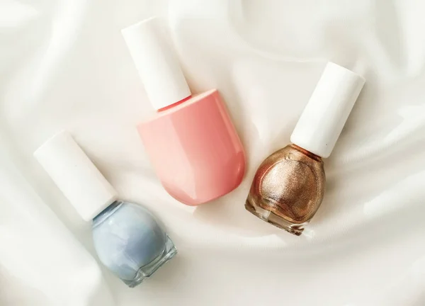 Nail polish bottles on silk background, french manicure products