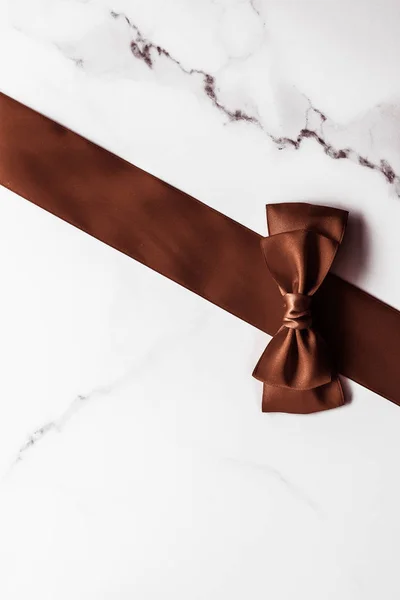 Chocolate brown silk ribbon on marble background, flatlay — Stock Photo, Image