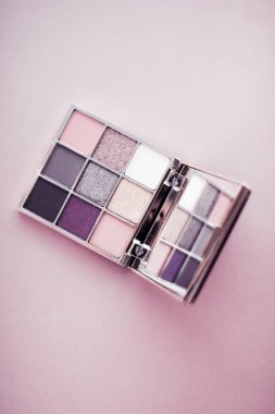Göz farı paleti ve pembe arka planda makyaj fırçası.