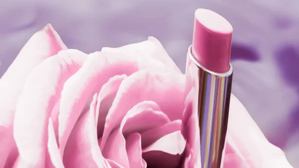 Pink lipstick and rose flower on liquid background, waterproof g