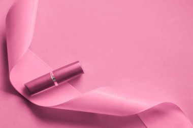 Pembe tatil arka planında lüks ruj ve ipek kurdele.