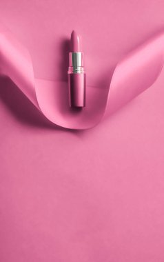 Pembe tatil arka planında lüks ruj ve ipek kurdele.