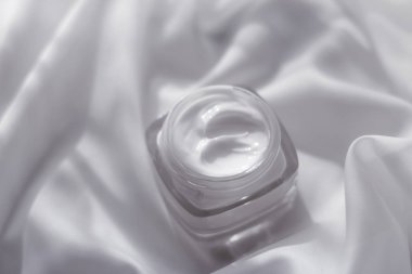 İpek arka planda yüz kremi nemlendirici kavanozu, nemlendirici cilt