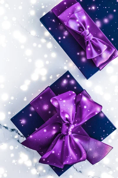 Winter holiday gift box with purple silk bow, snow glitter on ma