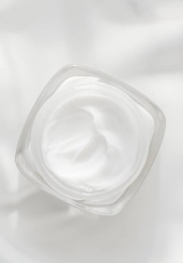İpek arka planda yüz kremi nemlendirici kavanozu, nemlendirici cilt