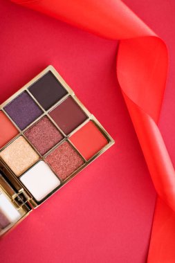 Kırmızı arka planda göz falı ve makyaj fırçası, göz farı