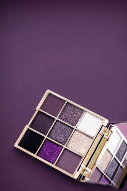 Göz falı paleti ve mor arka planda makyaj fırçası, göz farı