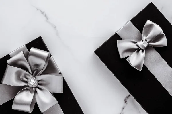 Luxusní sváteční dary se stříbrnou hedvábnou stuhou a lukem na mramorové b — Stock fotografie