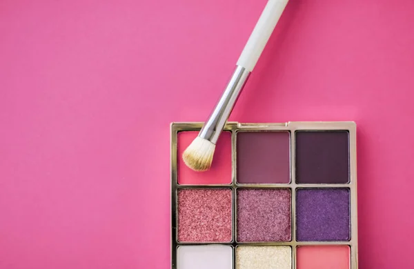 Paleta de sombra e pincel de maquiagem no fundo rosa, olho sombreado — Fotografia de Stock
