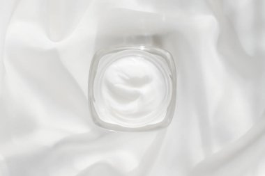 İpek arka planda yüz kremi nemlendirici kavanozu, nemlendirici cilt