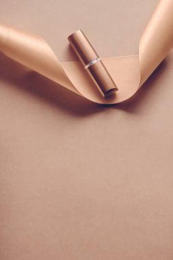 Bej rengi tatil arkaplanında lüks ruj ve ipek kurdele, mak