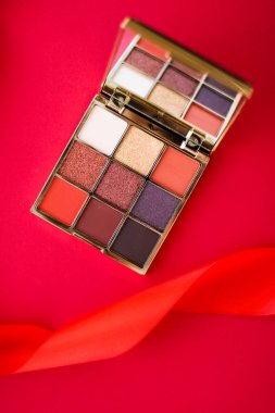 Kırmızı arka planda göz falı ve makyaj fırçası, göz farı