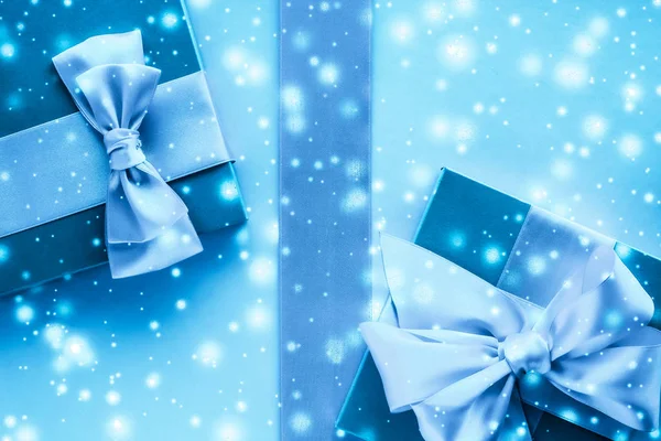 Winter vakantie geschenken en gloeiende sneeuw op bevroren blauwe achtergrond, — Stockfoto