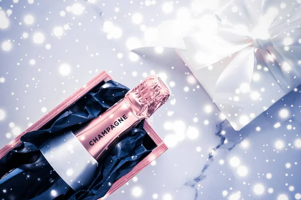 Champagne bottle and gift box on blue holiday glitter, New Years