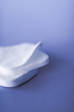 Mor arka planda organik pamuk pedleri, kozmetik ürünleri ve makyaj 