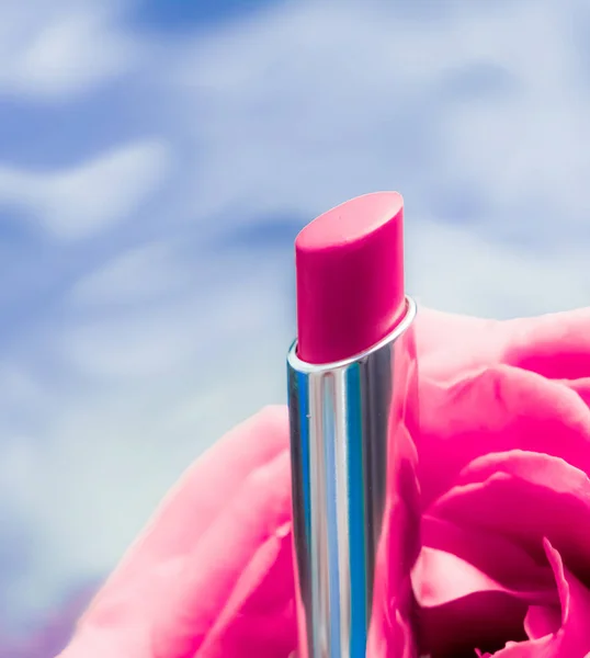 Pink lipstick and rose flower on liquid background, waterproof g