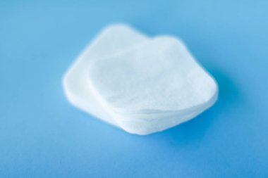 Mavi arka planda organik pamuk pedleri, kozmetik ürünleri ve makyaj malzemesi