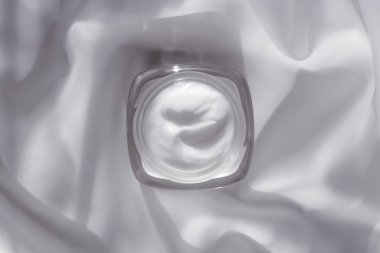 İpek arka planda yüz kremi nemlendirici kavanozu, nemlendirici cilt