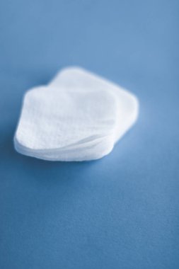 Mavi arka planda organik pamuk pedleri, kozmetik ürünleri ve makyaj malzemesi