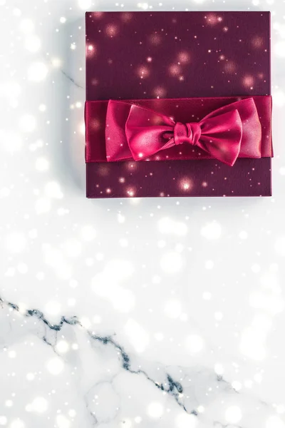 Winter holiday gifts with cherry silk bow and glowing snow on fr — Stock Photo, Image