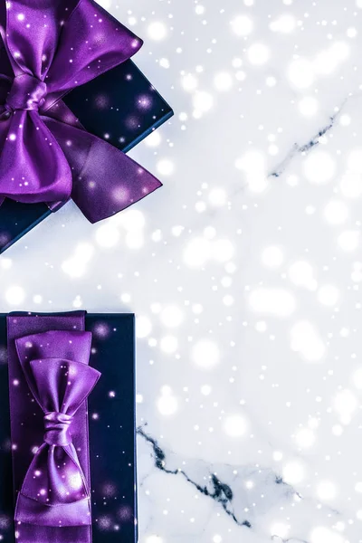 Winter holiday gift box with purple silk bow, snow glitter on ma — Stock Photo, Image