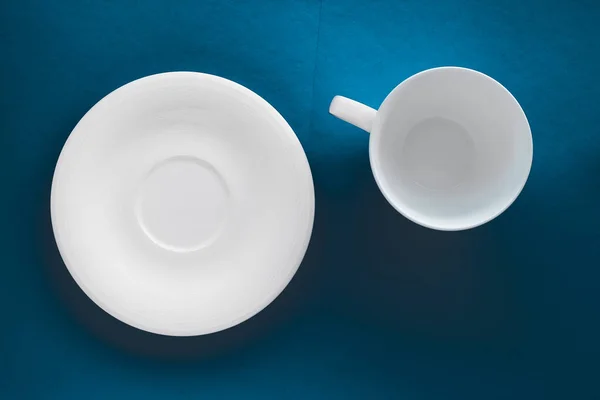 Ensemble de vaisselle en vaisselle blanche, tasse vide sur fond plat bleu — Photo