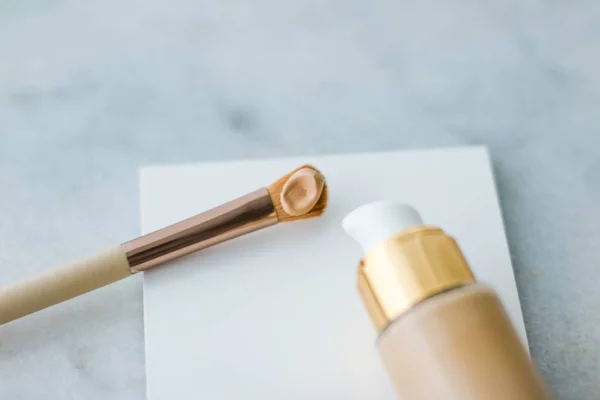 Makeup foundation bottle and contouring brush on marble, make-up