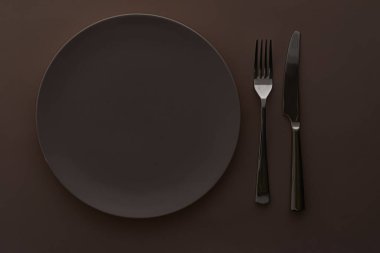 Koyu kahverengi arka planda boş tabak ve çatal bıçak seti, Şef Masa Dekorasyonu ve Menü Markası için üst masa takımı
