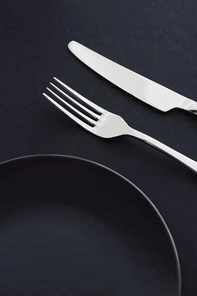 Pratos vazios e talheres em fundo preto, talheres premium para jantar de férias, design minimalista e dieta — Fotografia de Stock