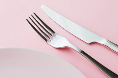 Boş tabak ve çatal bıçak seti pembe arka planda, en iyi sofra takımı şef masa dekorasyonu ve menü markalaşması için