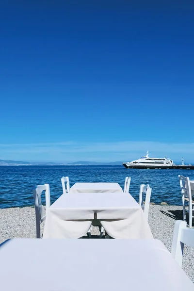 Empty restaurant by the Aegean sea and cruise boat — Stock Photo, Image