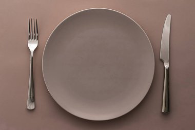 Boş tabak ve çatal bıçak seti kahverengi arka planda, şef masa dekorasyonu ve menü markalaşması için en üst masa takımı