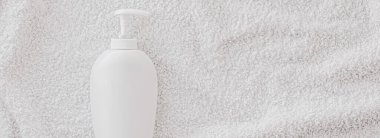 Beyaz havlu arka planında ürün modeli olarak boş etiket kozmetik kutu şişesi