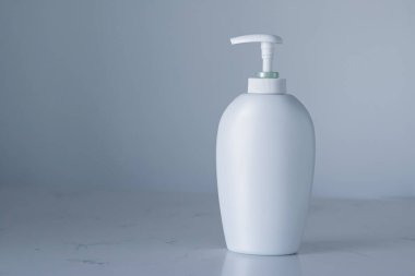 Gri arka planda ürün modeli olarak boş etiket kozmetik kutu şişesi