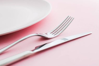 Boş tabak ve çatal bıçak seti pembe arka planda, en iyi sofra takımı şef masa dekorasyonu ve menü markalaşması için