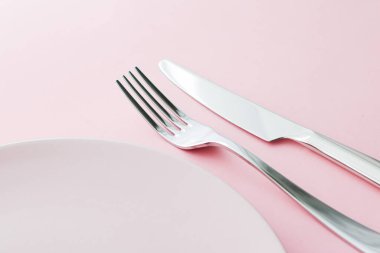 Boş tabak ve çatal bıçak seti pembe arka planda, en iyi sofra takımı şef masa dekorasyonu ve menü markalaşması için