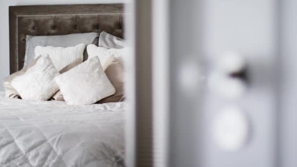 Dekorativní polštáře a polštáře na posteli v luxusním ložnicovém interiéru, otevřené dveře do pokoje, domácí výzdoba a design — Stock video
