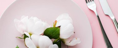 Pembe arka planda şakayık çiçekli yemek tabağı ve çatal bıçak seti. Etkinlik dekorasyonu ve menü markalaşması için en üst masa takımı.