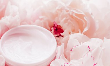 Lüks kozmetik krem kavanozu. Şakayık çiçeklerinin, vücut nemlendiricisinin ve güzellik markalarının arka planında yaşlanma karşıtı rutin bir ürün.