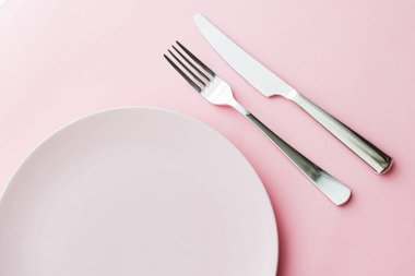 Boş tabak ve çatal bıçak seti pembe arka planda, en iyi sofra takımı şef masa dekorasyonu ve menü markalaşması için