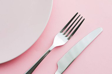 Boş tabak ve çatal bıçak seti pembe arka planda, en iyi sofra takımı şef masa dekorasyonu ve menü markalaşması için