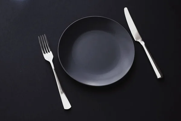 Пустые тарелки и столовые приборы на черном фоне, посуда премиум класса для праздничного ужина, минималистичный дизайн и диета — стоковое фото