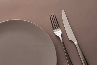 Boş tabak ve çatal bıçak seti kahverengi arka planda, şef masa dekorasyonu ve menü markalaşması için en üst masa takımı